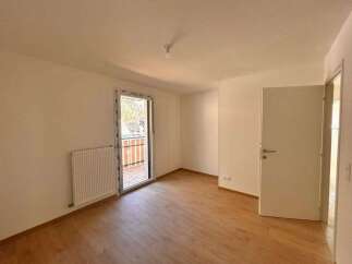 Discover this bright and airy room featuring a modern radiator and a large glass door leading to a balcony with scenic views.