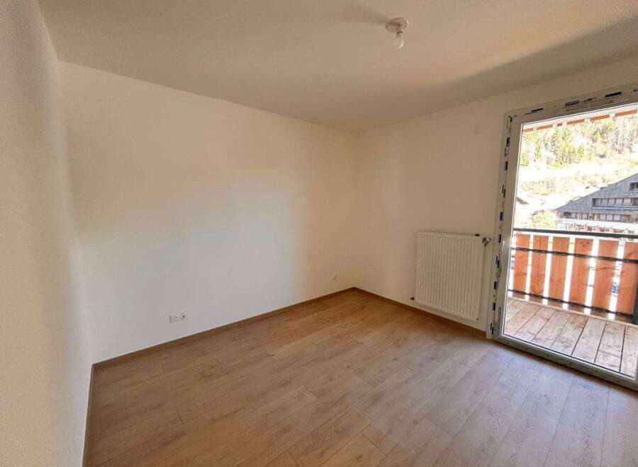Experience modern living in this bright and airy room featuring a sleek white radiator and a sliding glass door that opens to a charming balcony.