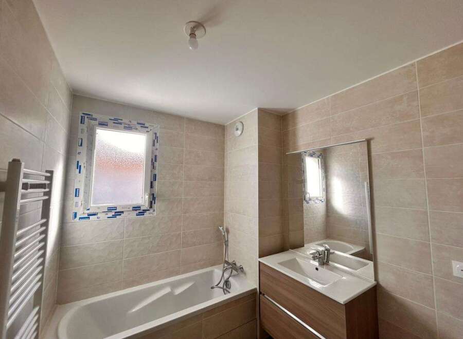 This modern bathroom features a spacious bathtub and a sleek vanity with a large mirror.