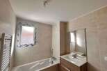 This modern bathroom features a spacious bathtub and a sleek vanity with a large mirror.