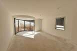 Discover this unfinished interior space, bathed in natural light from a large, curved window offering scenic views.