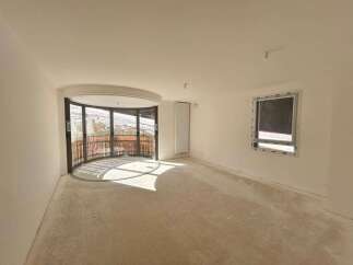 Discover this unfinished interior space, bathed in natural light from a large, curved window offering scenic views.