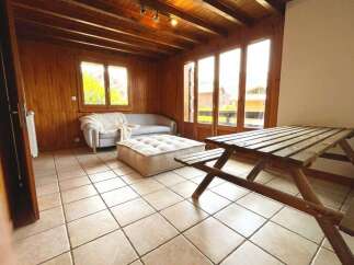 Experience rustic charm in this cozy living space featuring warm wooden paneling and a beamed ceiling.