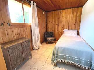 This cozy bedroom features warm wood paneling and a large window that floods the space with natural light.