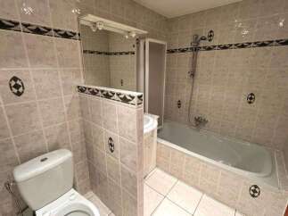 This bathroom features a classic tiled design with a bathtub and shower combination, perfect for relaxation.