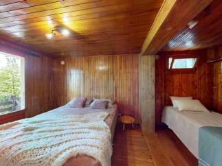 Experience rustic charm in this cozy wooden cabin bedroom, featuring two comfortable beds perfect for a relaxing getaway.