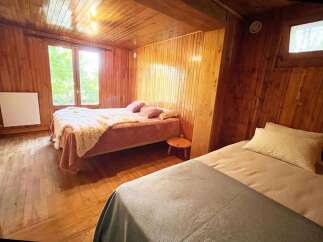 Experience cozy living in this charming wooden cabin bedroom, featuring two comfortable beds perfect for families or groups.