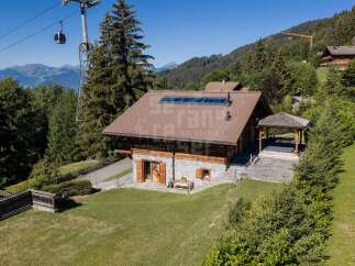 Experience luxury mountain living in this stunning chalet, featuring a modern hot tub area under a charming gazebo and expansive mountain views.