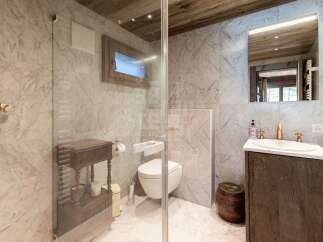 Experience rustic luxury in this charming bathroom, featuring elegant marble walls and a warm wooden ceiling.