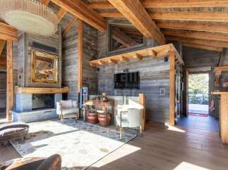 Experience luxury mountain living in this stunning chalet, featuring a grand fireplace and exposed wooden beams that create a warm, rustic ambiance.