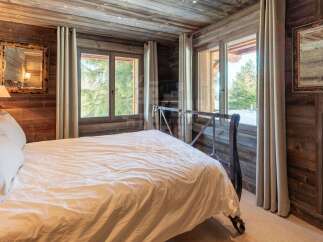 Experience rustic charm in this cozy bedroom, featuring warm wooden walls and ceiling, complemented by a stylish metal bed frame.