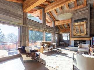 Experience rustic luxury in this stunning mountain lodge living room, featuring a grand stone fireplace and exposed wooden beams.
