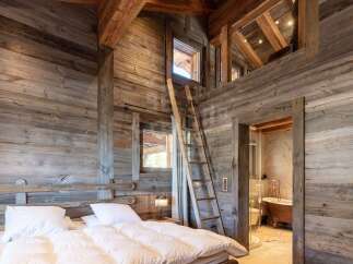 Experience rustic charm in this unique bedroom featuring exposed wooden beams and walls, creating a cozy mountain lodge ambiance.