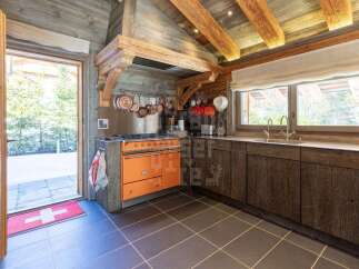 Experience rustic charm in this mountain kitchen, featuring a vibrant orange range and exposed wooden beams.