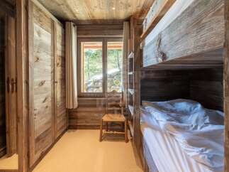 Experience rustic charm in this cozy cabin bedroom, featuring a built-in bunk bed with dark wood accents and crisp white linens.