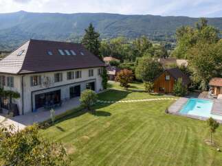 Discover this stunning property featuring a spacious main house with large windows and a charming wooden guesthouse.