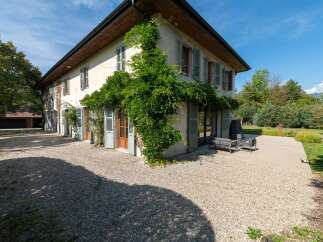 Charming property featuring a large house with traditional shutters and lush greenery climbing the facade.