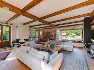 Experience rustic charm and modern comfort in this spacious living room, featuring exposed wooden beams and a large fireplace.