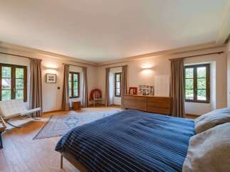 This spacious bedroom features a large, comfortable bed with a blue striped duvet, perfect for a restful night's sleep.