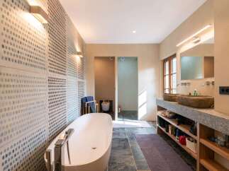 Experience luxury in this stunning bathroom featuring a freestanding soaking tub and a unique stone double vanity.