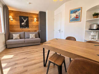 Experience cozy living in this charming apartment featuring a comfortable grey sofa adorned with decorative pillows, set against a rustic wooden accent wall.