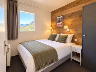 Experience cozy mountain living in this charming bedroom, featuring a comfortable queen-sized bed adorned with plush pillows and a warm throw.