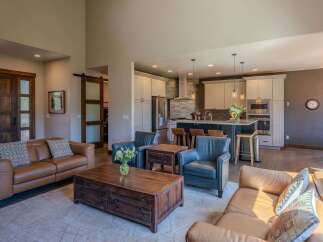 Experience luxury living in this open-concept home featuring a spacious living area with plush leather seating and a rustic wooden coffee table.