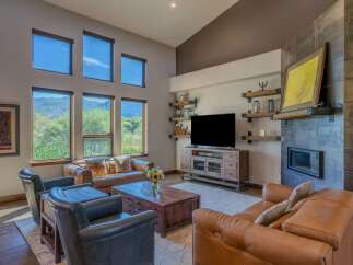 Experience breathtaking mountain views from this stunning living room, featuring a dramatic vaulted ceiling and expansive windows.