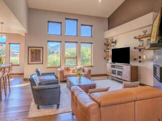 Experience luxury living in this spacious great room, featuring a soaring vaulted ceiling and abundant natural light from large windows overlooking scenic mountain views.