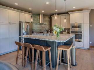 This modern kitchen boasts a large granite island with comfortable bar stools, perfect for casual dining or entertaining.