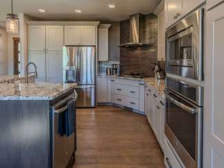 Experience luxury in this modern kitchen featuring sleek stainless steel appliances, including a double oven and a built-in microwave.