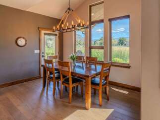 Experience elegant dining in this spacious room, featuring a large wooden table with seating for six and a striking industrial chandelier overhead.