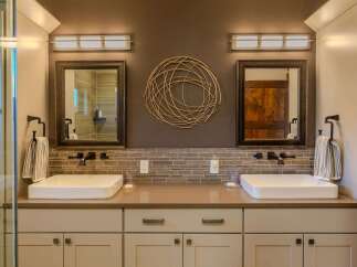 This luxurious master bathroom features a dual vanity with modern vessel sinks and sleek black faucets, complemented by a stylish tiled backsplash.
