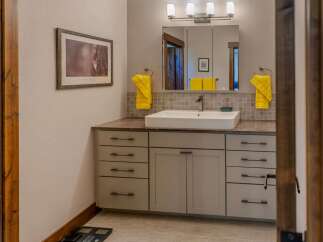 This modern bathroom features a sleek vanity with ample storage, complemented by a vessel sink and a tiled backsplash.