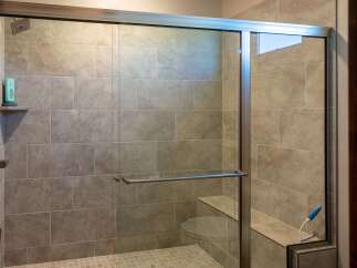 Experience luxury in this modern bathroom featuring a spacious walk-in shower with elegant tile work and a built-in bench.