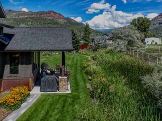 Experience the ultimate mountain lifestyle with this stunning property, featuring a covered outdoor living space perfect for entertaining, complete with a grill and comfortable seating.