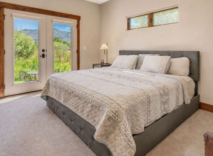 Experience serene living in this beautifully appointed bedroom, featuring a plush king-sized bed with a tufted headboard and a cozy quilted comforter.
