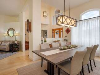 Experience elegant dining in this spacious room, featuring a large wooden table set for gatherings and illuminated by a striking modern chandelier.