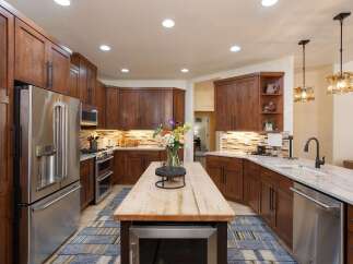 This spacious kitchen boasts custom wood cabinetry and a large island with a butcher block countertop, perfect for meal preparation and casual dining.