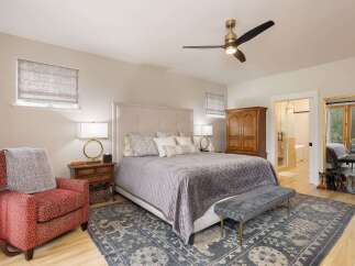 Experience ultimate comfort in this master bedroom, featuring a plush upholstered headboard and a luxurious quilted bedspread.