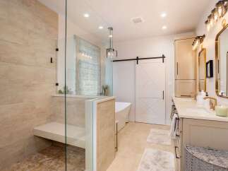 Experience luxury in this stunning bathroom featuring a spacious walk-in shower with elegant tilework and a built-in bench.