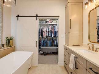 Step into a luxurious master bathroom featuring a freestanding soaking tub and a spacious walk-in closet accessible via a stylish barn door.