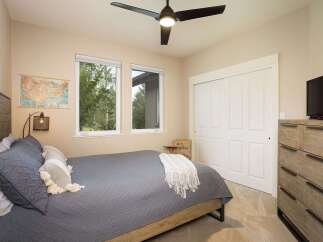 This inviting bedroom features a comfortable queen-size bed with a stylish grey quilted comforter and decorative pillows.