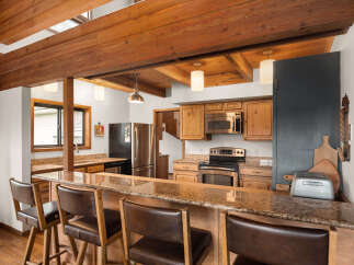 Experience rustic charm in this kitchen featuring exposed wooden beams and a spacious granite-topped breakfast bar perfect for casual dining.