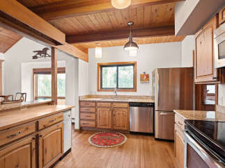 Experience rustic charm in this spacious kitchen featuring warm wood cabinetry and exposed beams.
