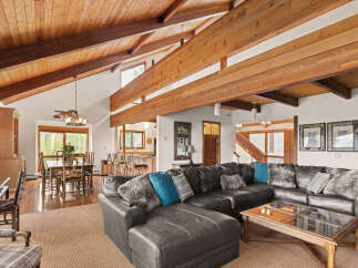 Experience rustic charm in this spacious living area featuring a vaulted wood-beamed ceiling and a large sectional sofa perfect for gatherings.