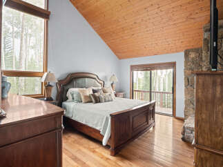 Experience rustic elegance in this charming bedroom, featuring a luxurious king-size bed adorned with plush pillows and a light blue quilted coverlet.