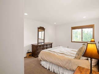 This charming bedroom features a spacious bed with a light tan comforter, complemented by a dark wood dresser and mirror.