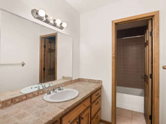 This bathroom features a spacious vanity with a tiled countertop and a large mirror, perfect for your morning routine.