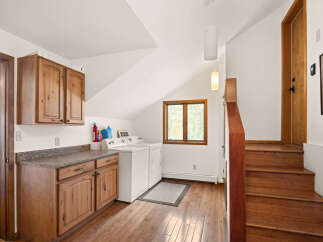 Discover the convenience of this charming laundry area, featuring a stacked washer and dryer and ample cabinet storage.